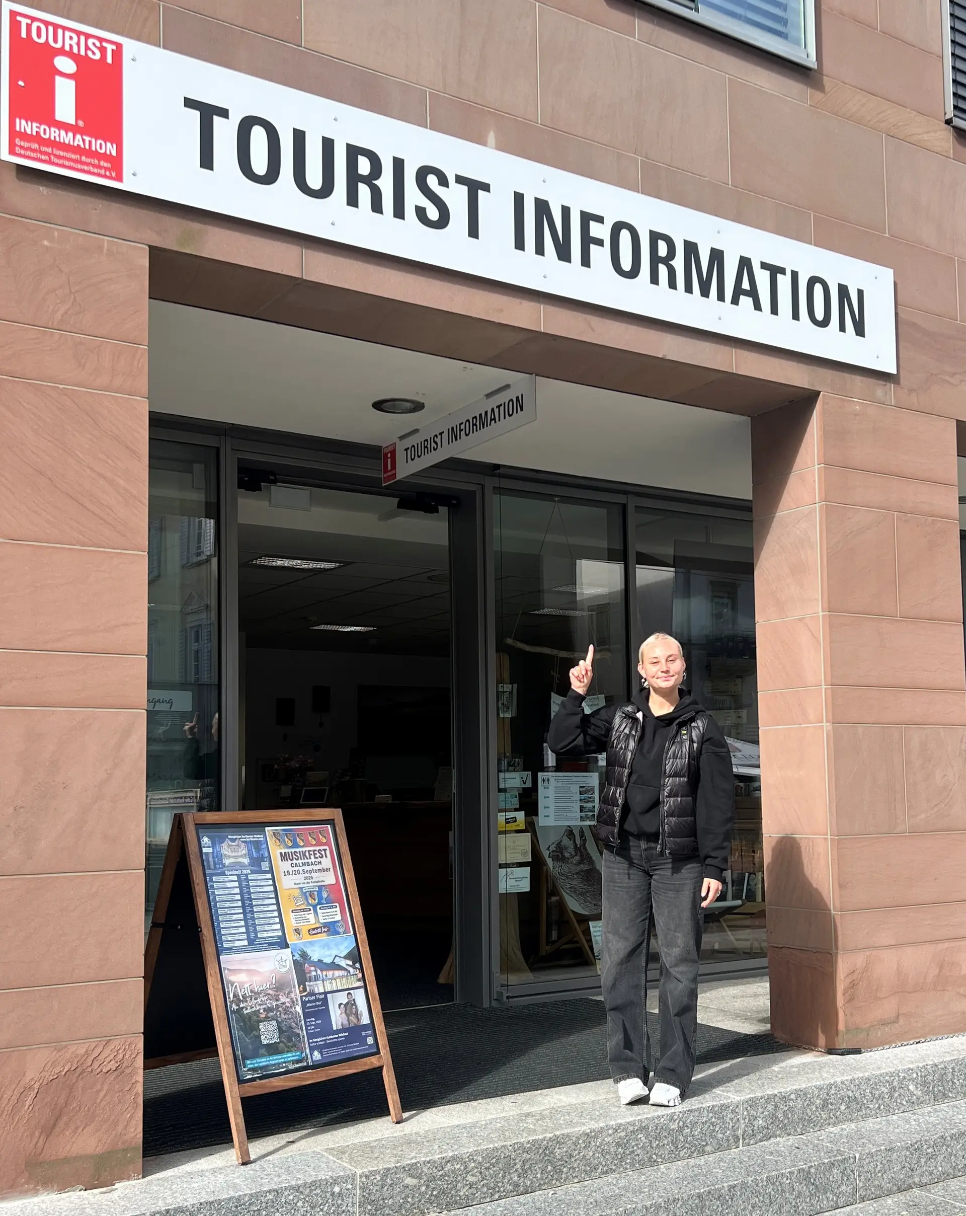 Firmenschild mit rotem „i“ als Informationszeichen an der Tourist Information.