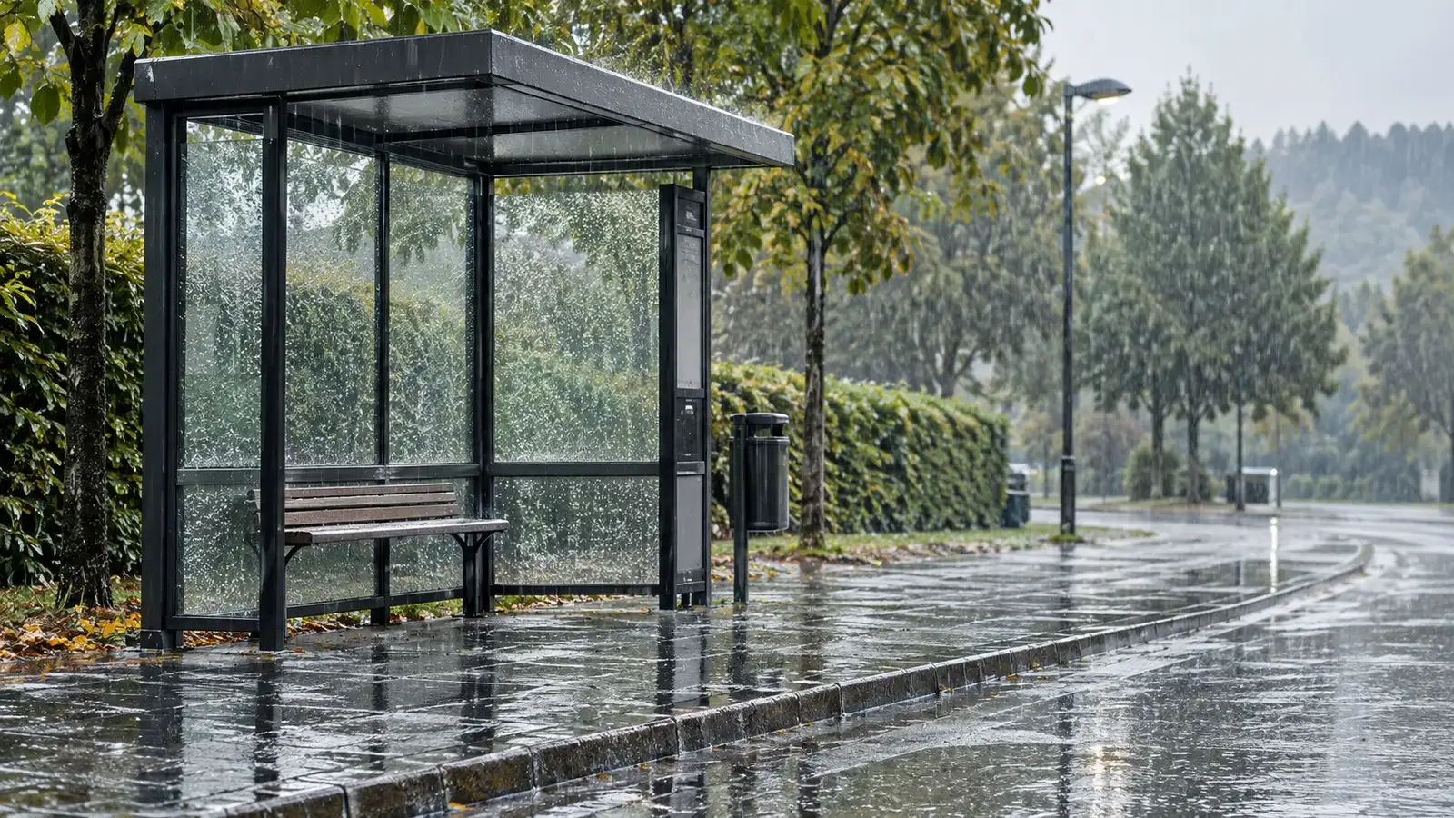 Regen an einer Haltestelle. Neutrale Alltagskulisse ohne behaupteten Aufnahmeort.