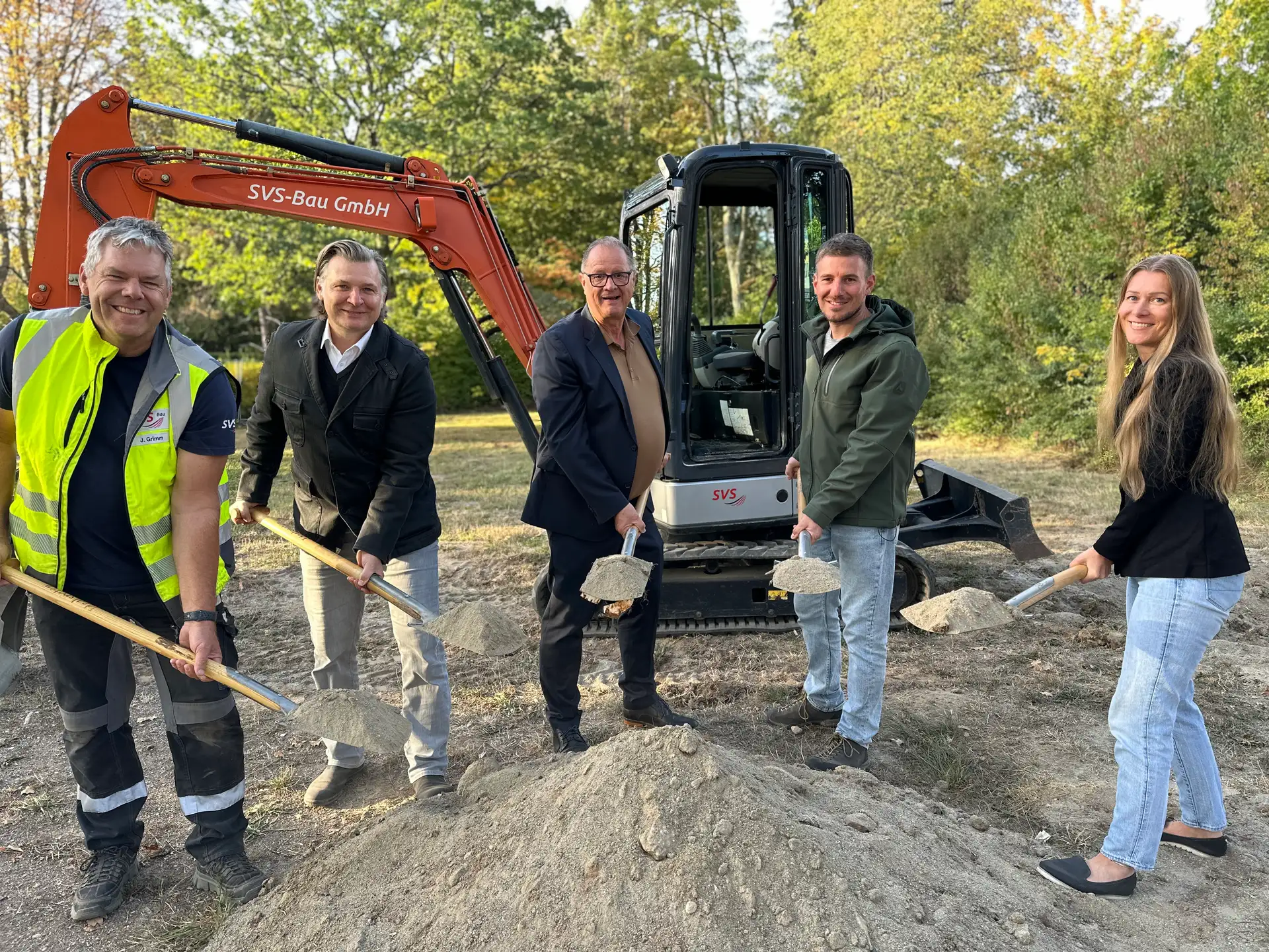 Mehrere Personen beim Spatenstich für einen neuen Spielplatz: Sie greifen zum Spaten, um den Beginn der Bauarbeiten anzustoßen.