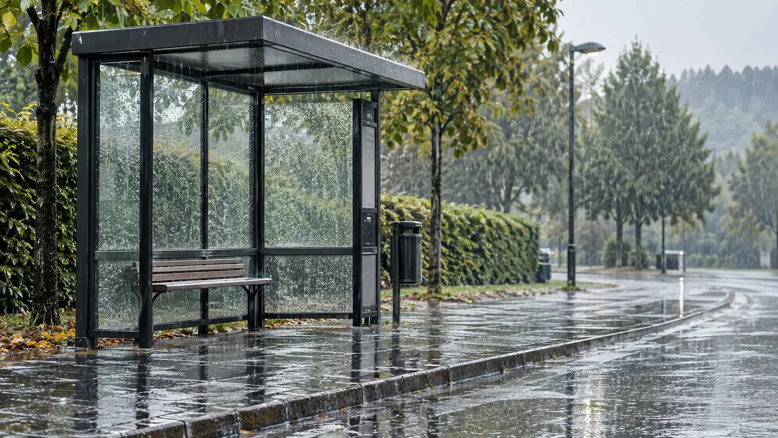 Regen an einer Haltestelle. Neutrale Alltagskulisse ohne behaupteten Aufnahmeort.
