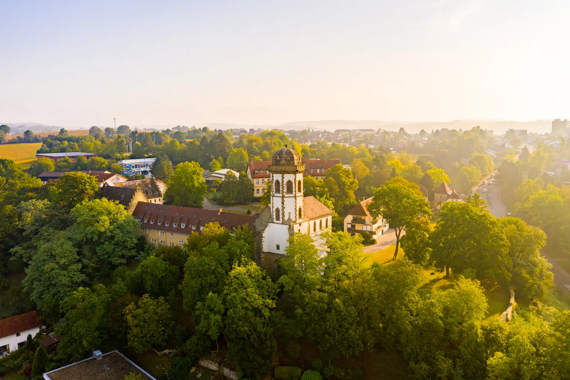 Luftaufnahme bei Sonnenaufgang mit Blick auf die ehemalige Stift- und Klosterkirche Stift Sunnisheim in Sinsheim.