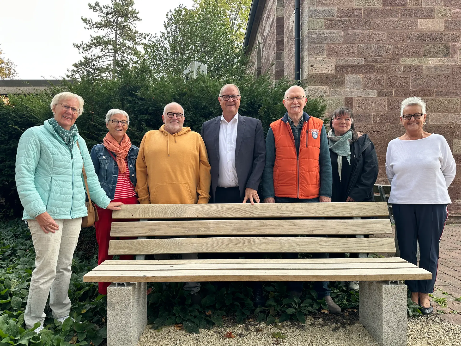 Zwei neue Sitzbänke stehen vor der Kapelle des Villinger Friedhofs; im Hintergrund sind Personen bei der Übergabe zu sehen.