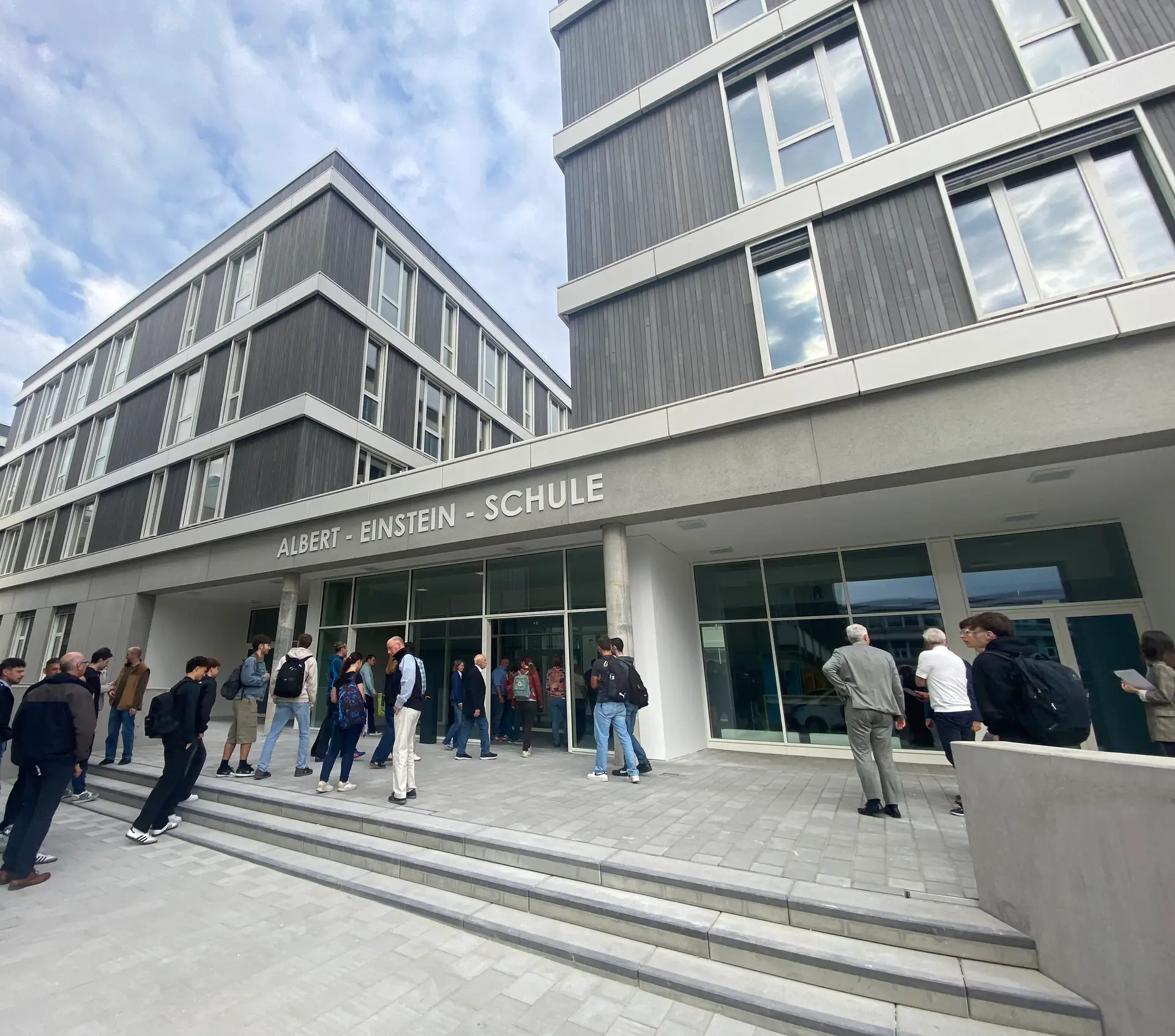 Gruppenfoto bei der offiziellen Einweihung der Albert-Einstein-Schule: Personen stehen in Reihen vor dem Gebäude.