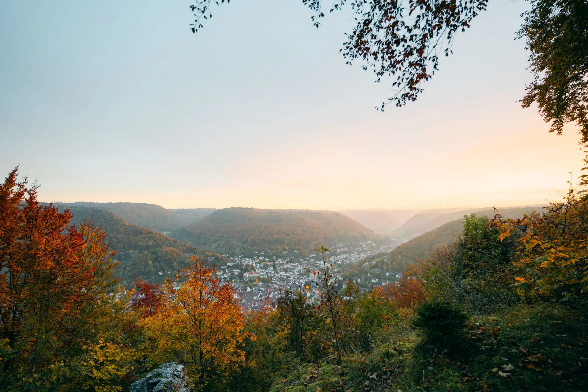 Blick auf Bad Urach im Herbst mit bewaldeten Hängen und herbstlicher Vegetation